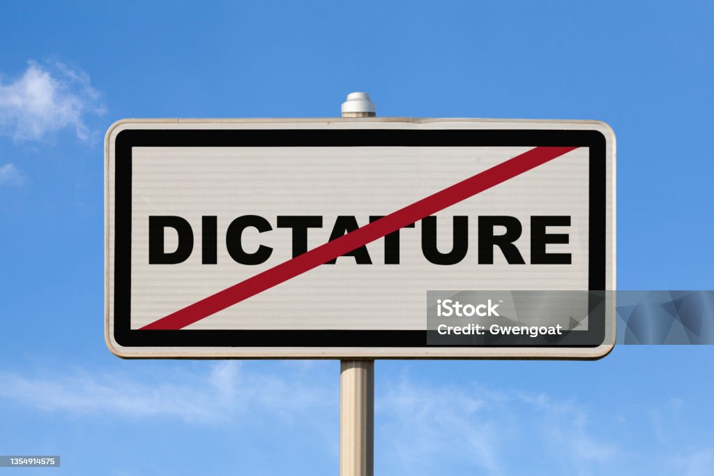 Dictature - French exit city sign A French exit city sign against a blue sky with written in the middle Dictature. Dictator Stock Photo