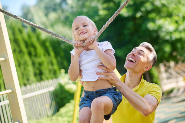 istock Dad holding his daughter while she climbing 1354917884