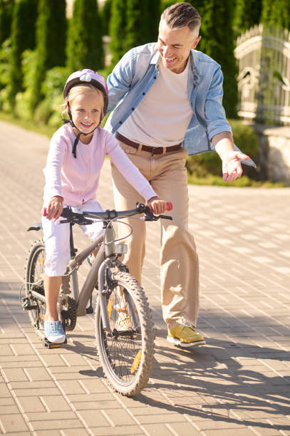 istock A man supporting a girl while she riding a bike 1354918054