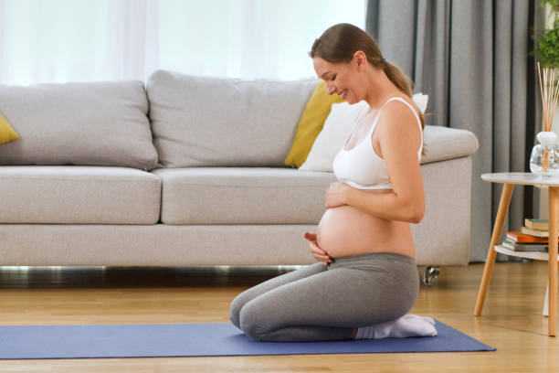 istock Young pregnant woman massaging the belly while doing relaxation exercise indoors 1354918325