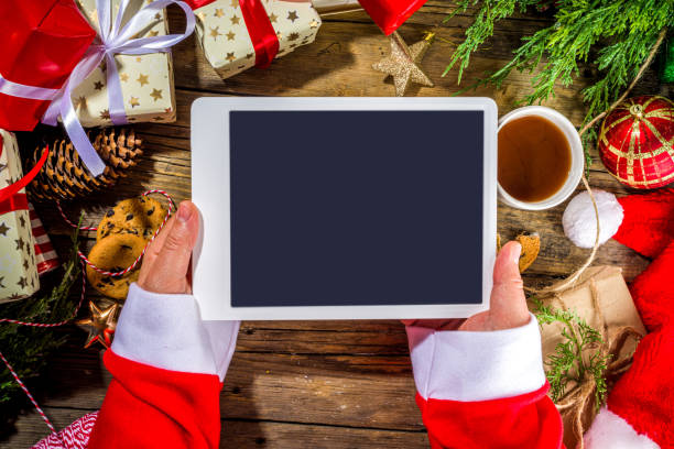 istock Santa hands with tablet pc, Christmas background 1354920528