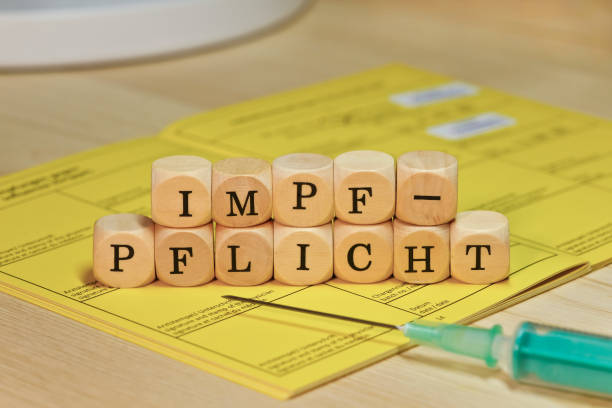 Mandatory vaccination / Covid-19 pandemic The word "Impfpflicht" in German language, placed on a yellow vaccination certificate. mandate stock pictures, royalty-free photos & images