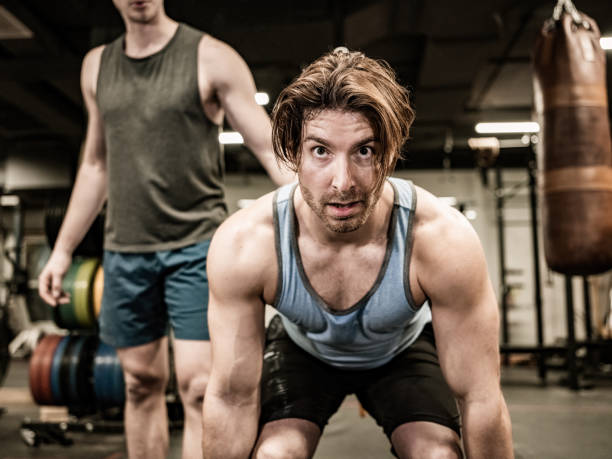 istock Young Man lifting weights with his trainer in the Gym 1354926602