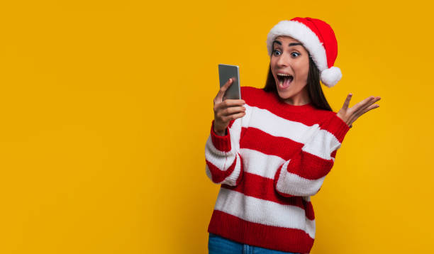 Excited beautiful shouting woman with smart phone in hands due to she win some present in Christmas time stock photo