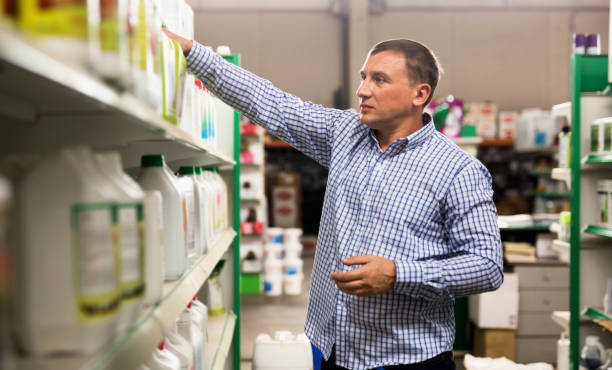 istock Man choosing liquid fertilizer in plastic bottle in hypermarket 1354927954