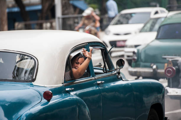 キューバの女性は車から友人に手を振る。 - cuba car chevrolet havana ストックフォトと画像