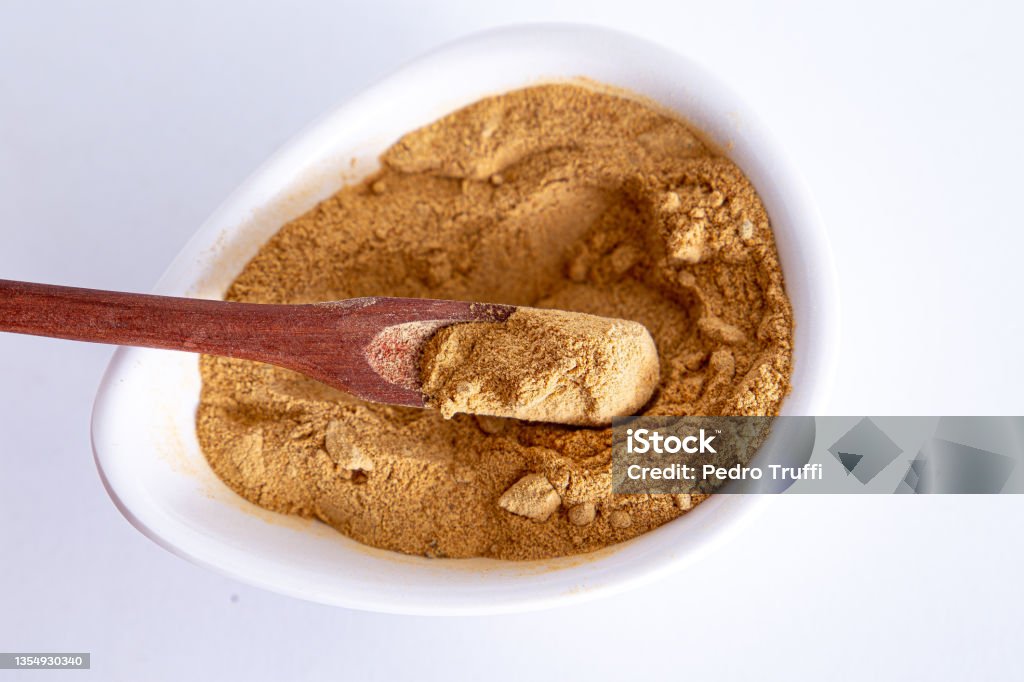 Peruvian maca powder with rustic wooden spoon on a white background. selective focus Peruvian maca powder with rustic wooden spoon on a white background. selective focus. Alternative Medicine Stock Photo