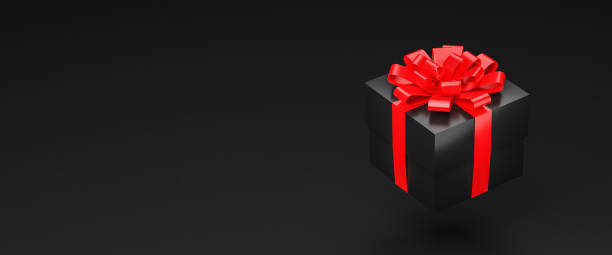 istock A black gift box with red ribbon and bow hovering over a black background. Web banner size with copy space. 1354930738