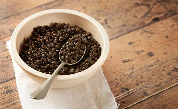 Beluga or Black Lentil in a bowl on wooden background. Empty space for text. Vegetarian food concept. Macrobiotic diet.