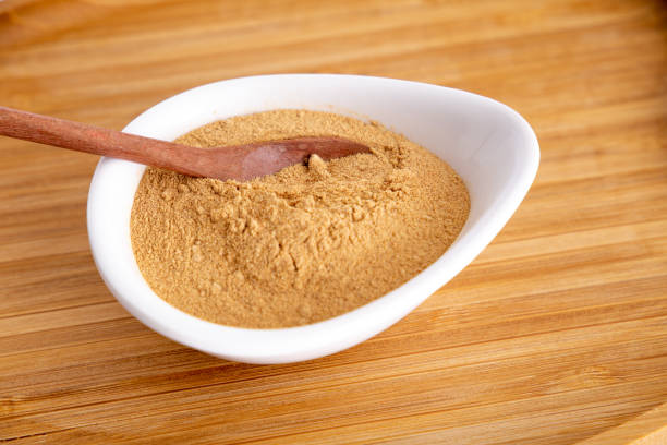 istock pot of Peruvian Maca powder under a bamboo tray, selective focus, on white background. 1354931980