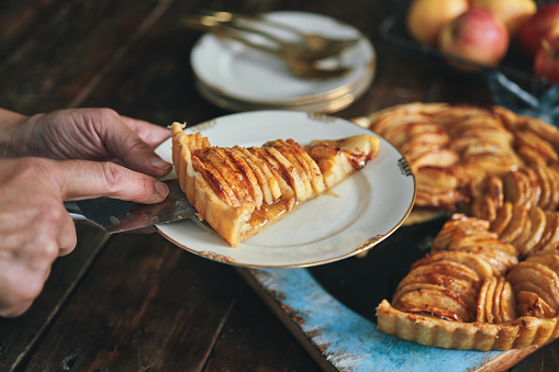 Traditional autumn apple pie. Sweet Thanksgiving dinner, fall seasonal cake with apples, cinnamon, nuts and caramel, with vanilla ice cream scoop ball, on wooden cosy background