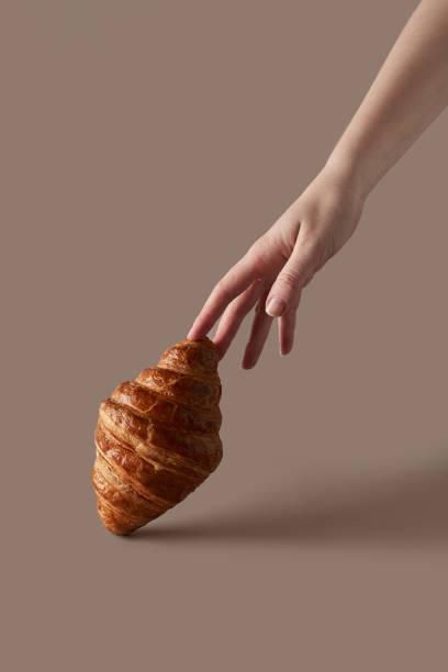 istock lush croissant on a beige background with a woman's hand 1354936517