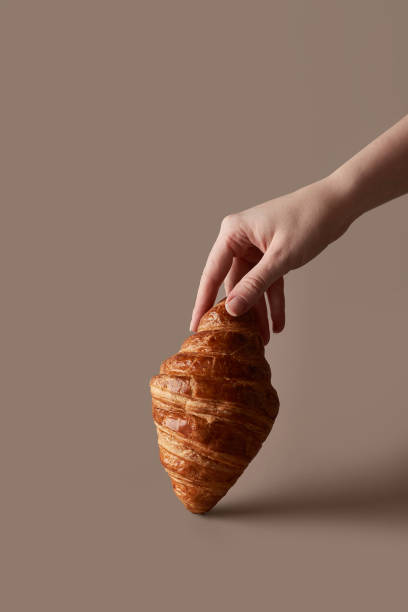 istock lush croissant on a beige background with a woman's hand 1354936526