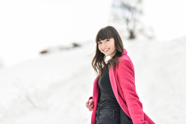 istock Female Smiling While Walking In Fresh Mountain Snow Wearing Pink Coat 1354938007