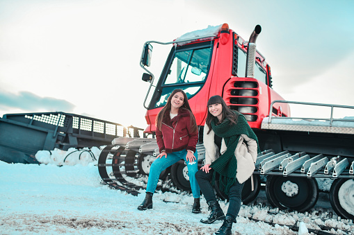 Females Enjoying Sitting On Snow Removal Vehicle While Having Winter Mountain Holiday