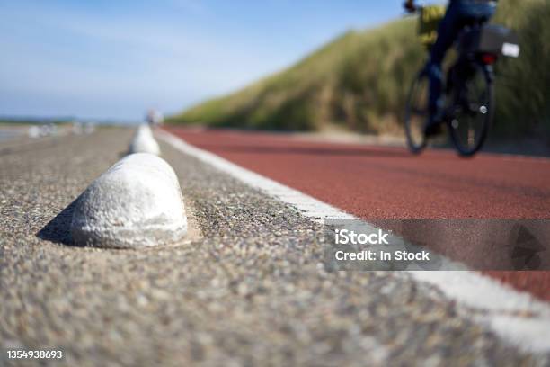 Bicycle Path In South Holland Part Of A Male Dark Clothed Cyclist Depth Of Field Big Beach Dune With Grass Netherlands Schouwenduiveland Brouwersdam Stock Photo - Download Image Now