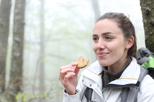 Happy trekker eating cookie in a forest