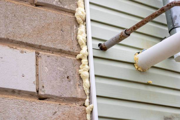Wall cladding with siding. Foaming insulation with polyurethane foam. Gas and ventilation pipes stock photo