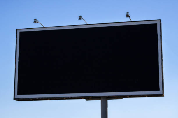 istock Large outdoor city black empty billboard on the blue sky. 1354943132