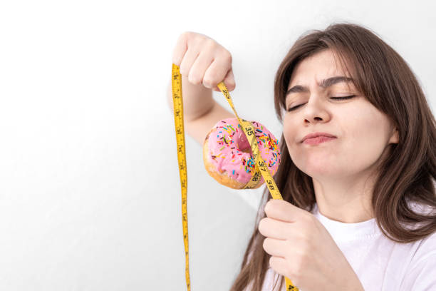 junge frau mit donut mit maßband, isoliert. - weight training audio stock-fotos und bilder