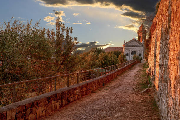 Montalcino, Tuscany, Italy. August 2020. Amazing image at the golden hour. A church just outside the walls of the historic village is enveloped in the warm light of the sunset.