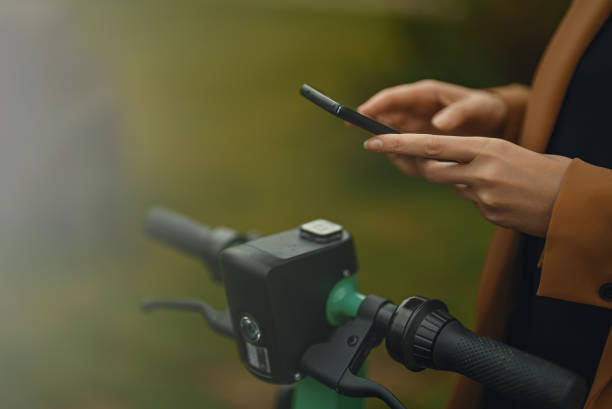 Woman using app on smartphone to unlock electric scooter on the street. stock photo