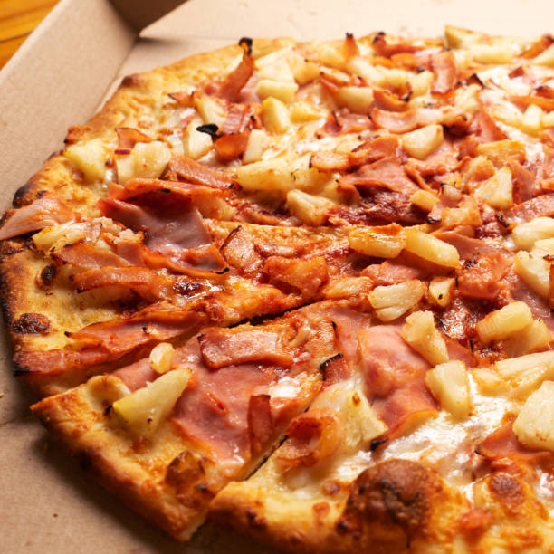 istock Ham and pineapple pizza called hawaiian on a wooden background 1354952241