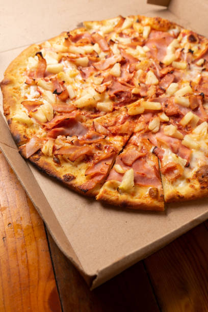 istock Ham and pineapple pizza called hawaiian on a wooden background 1354952518
