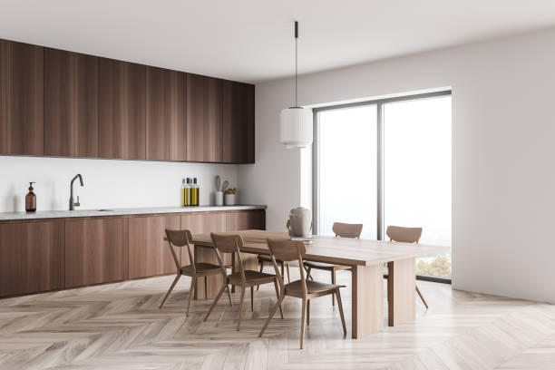 istock Minimalist dark wood kitchen with light wood dining table. Corner view. 1354954394