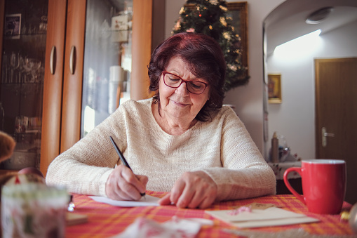One retired woman enjoying her afternoon activity of writing letters with pen and ink