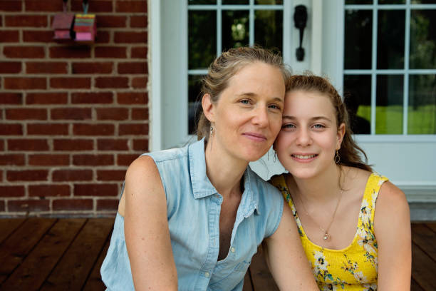Real family portrait of mother and teenage daughter on home porch in summer. stock photo