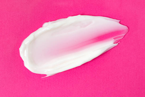istock Swatch of white cream on the pink background. 1354957510