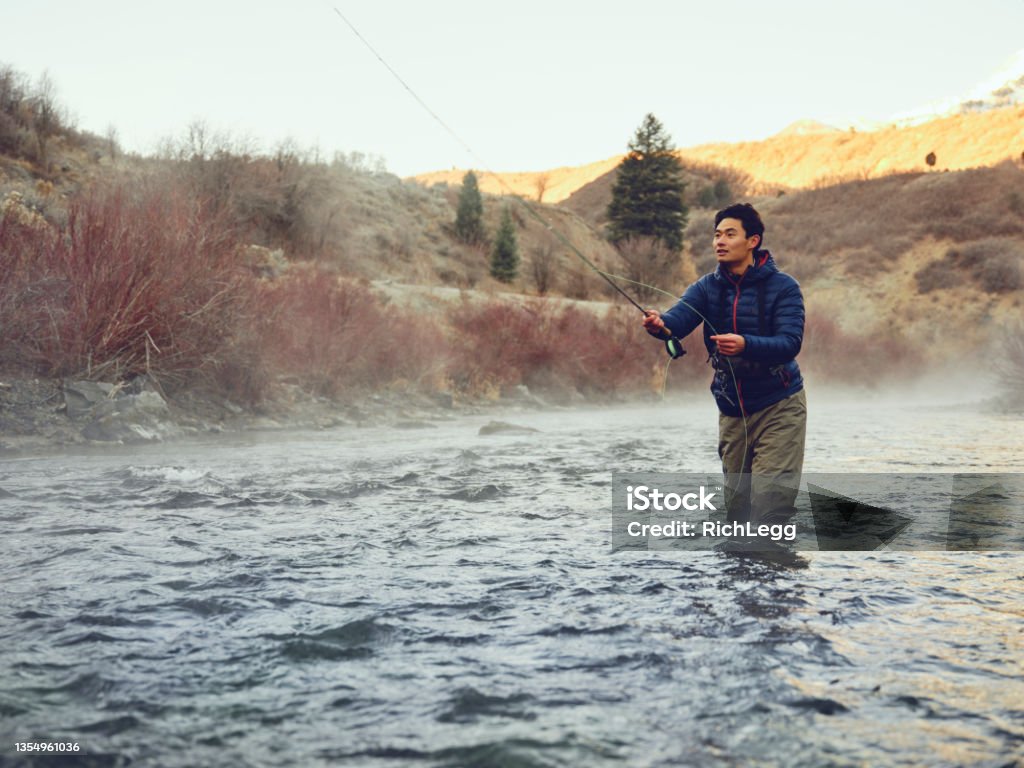 Asian Man on Provo River Fly Fishing in Utah An Asian Korean man, fly fishing on the Provo River in Utah during winter. Fishing Stock Photo