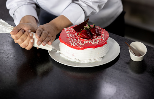 Close-up on a chef decorating a dessert at a pastry shop - food and drink concepts
