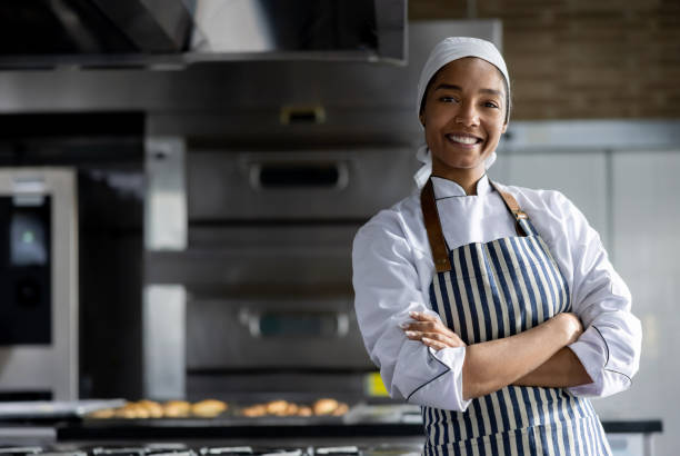 Happy African American woman working at the bakery making bread