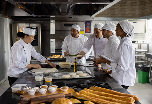 Head chef teaching a baking class at a cooking academy and talking to her students