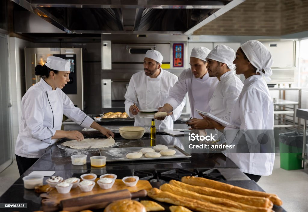Head chef teaching a baking class at a cooking academy Head chef teaching a baking class at a cooking academy and talking to her students Food and Drink Stock Photo