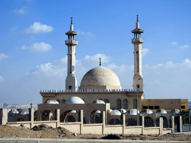 istock Big white Muslim mosque in Egypt on cloudy sky background,  oriental Islamic architecture with minarets and domes at daylight, white Islamic mosque for prayers 1354962908