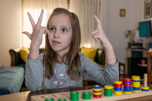 Girl counts on her fingers while playing whit mathematical toy in living room