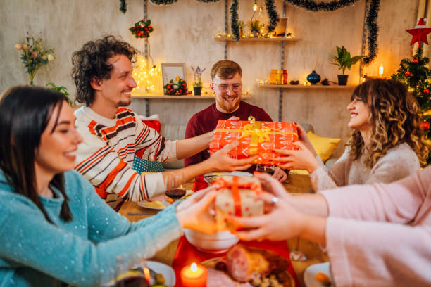istock Friends giving gifts to each other while sitting at table 1354966054