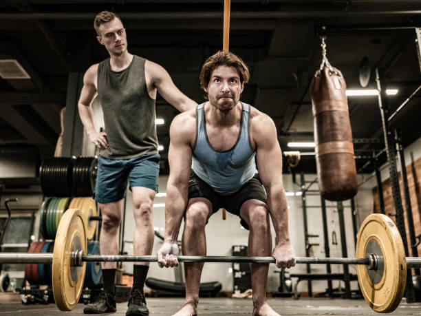 istock Young Man lifting weights with his trainer in the Gym 1354966951