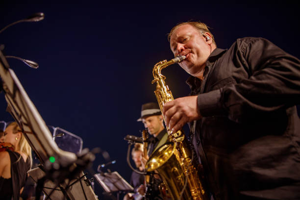 male musician playing saxophone under blue night sky - band 40s imagens e fotografias de stock