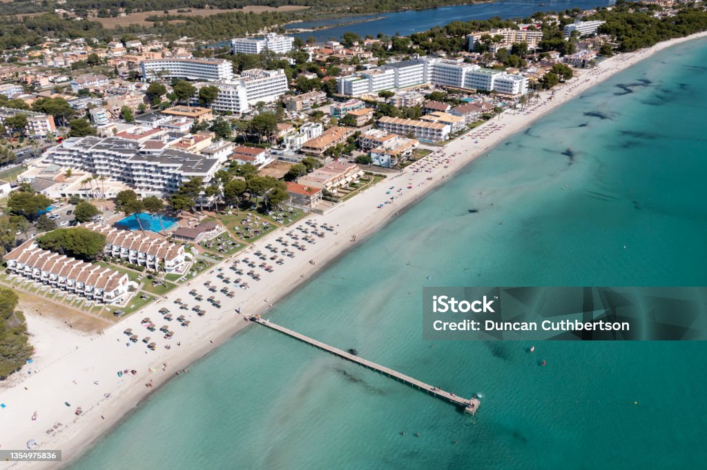 Aerial drone photo of the beach front on the Spanish island Majorca Mallorca, Spain showing the beach known as Platja de Muro in the village of Alcúdia on a sunny summers days Harbor Stock Photo
