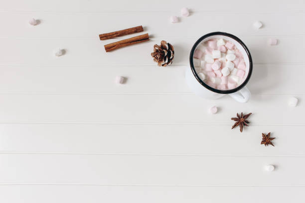 istock Christmas styled composition. Hot chocolate, marshmallow,cinnamon sticks, anise stars. Pine cones on white wooden table background. Festive winter breakfast concept. Flat lay, top view, copy space. 1354978185