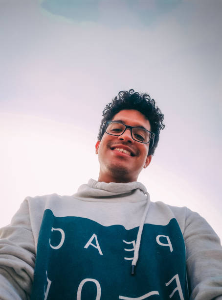 istock A young happy man with glasses smiling on a sky background. 1354980719