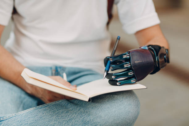 istock Young disabled man writes in notebook with pen in artificial prosthetic hand. 1354988027