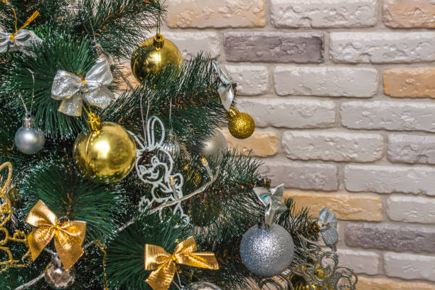 istock Mockup with decorated Christmas tree. Composition with gold and silver baubles, bows, animals, bells, lit garlands. Copy-space on the decorative brick wall background. Close-up, selective focus 1354989688