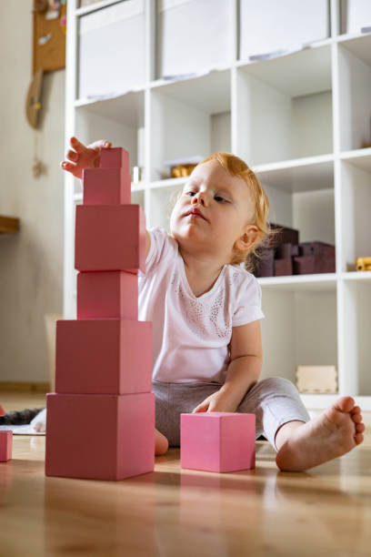 istock Cheerful toddler arrangement pink cubes assembling tower educational Maria Montessori materials 1354989922