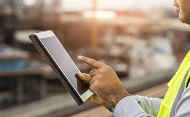 istock Engineer man or architect use tablet with white safety helmet in city construction site . Standing on rooftop building construction at capital. 1354994671
