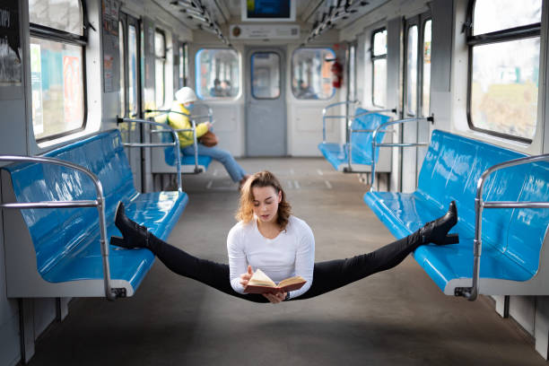 flexible weibliche yogi-lesebuch in der u-bahn-kutsche sitzend in gymnastik-split. konzept von inspiration, harmonie und gesundheit. - the splits flexibility yoga teenage girls stock-fotos und bilder